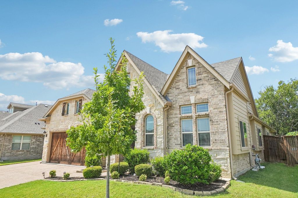French country style house with stone siding, driveway, a shingled roof, and a garage