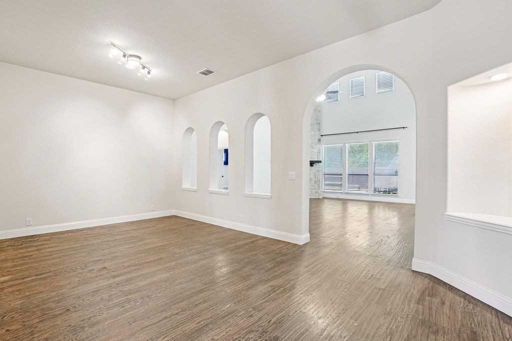 Spare room featuring arched walkways and dark wood-style flooring