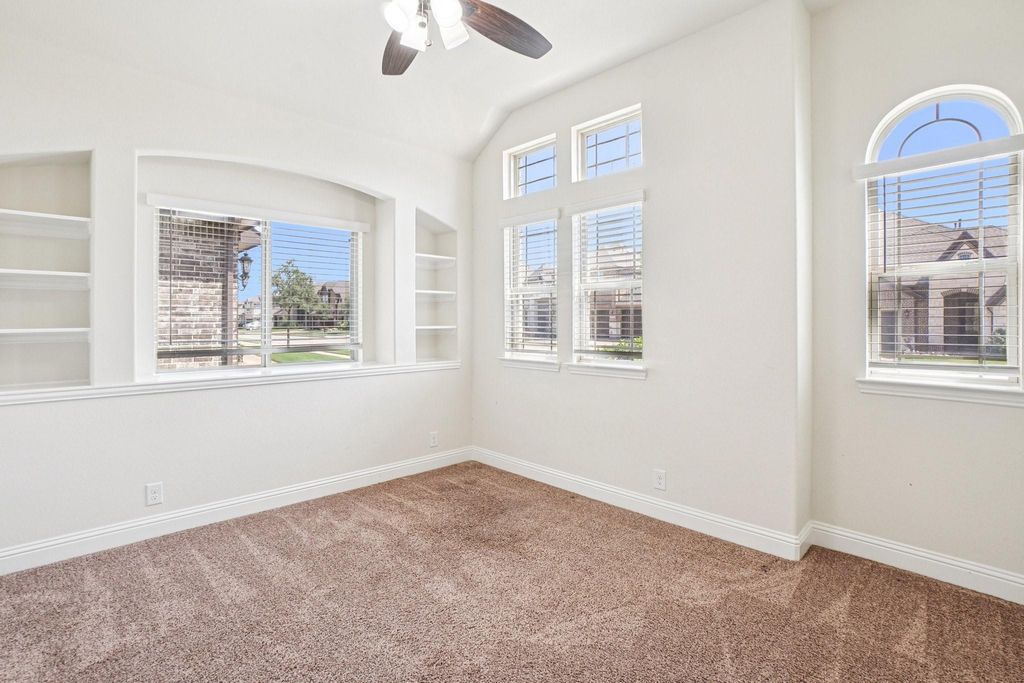 Unfurnished room with built in shelves, light colored carpet, a ceiling fan, and lofted ceiling