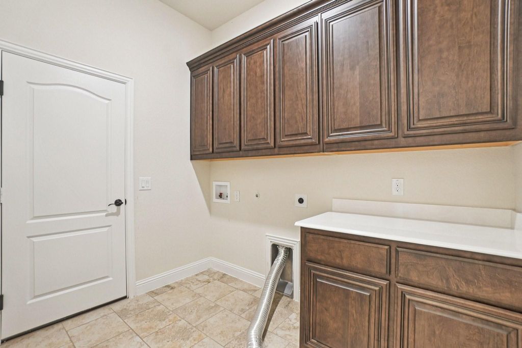 Laundry area with hookup for a gas dryer, electric dryer hookup, cabinet space, hookup for a washing machine, and light tile patterned floors