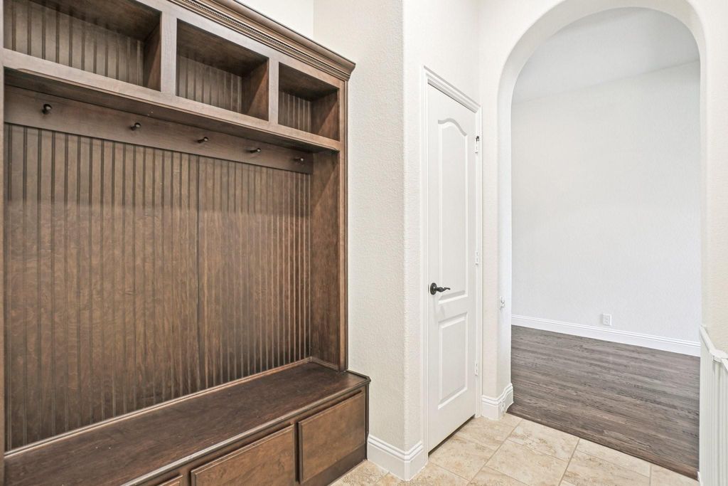 Mudroom featuring arched walkways and light tile patterned floors