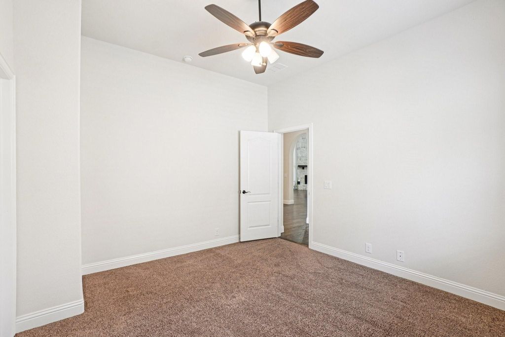Empty room with carpet floors and a ceiling fan