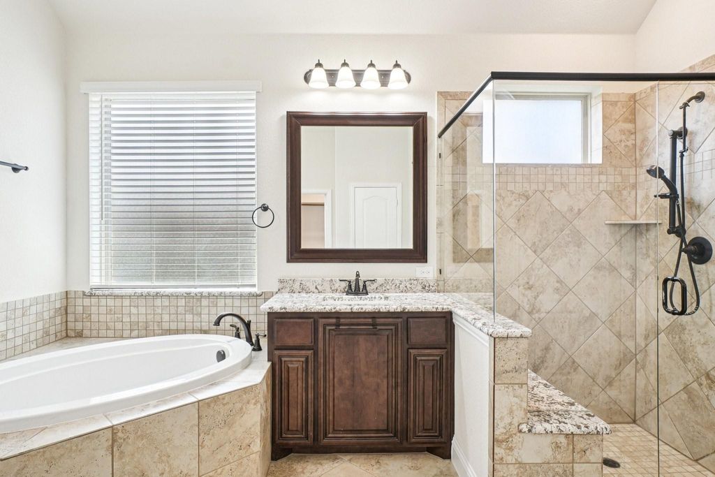 Full bathroom featuring a stall shower, a garden tub, and vanity