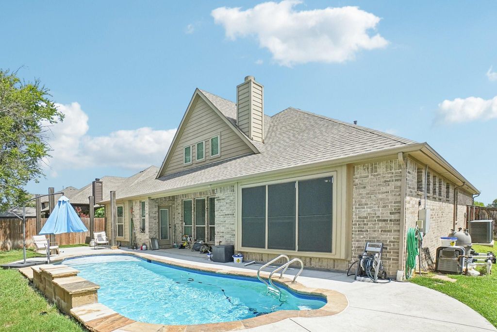 Back of property featuring a patio area, roof with shingles, a chimney, and brick siding
