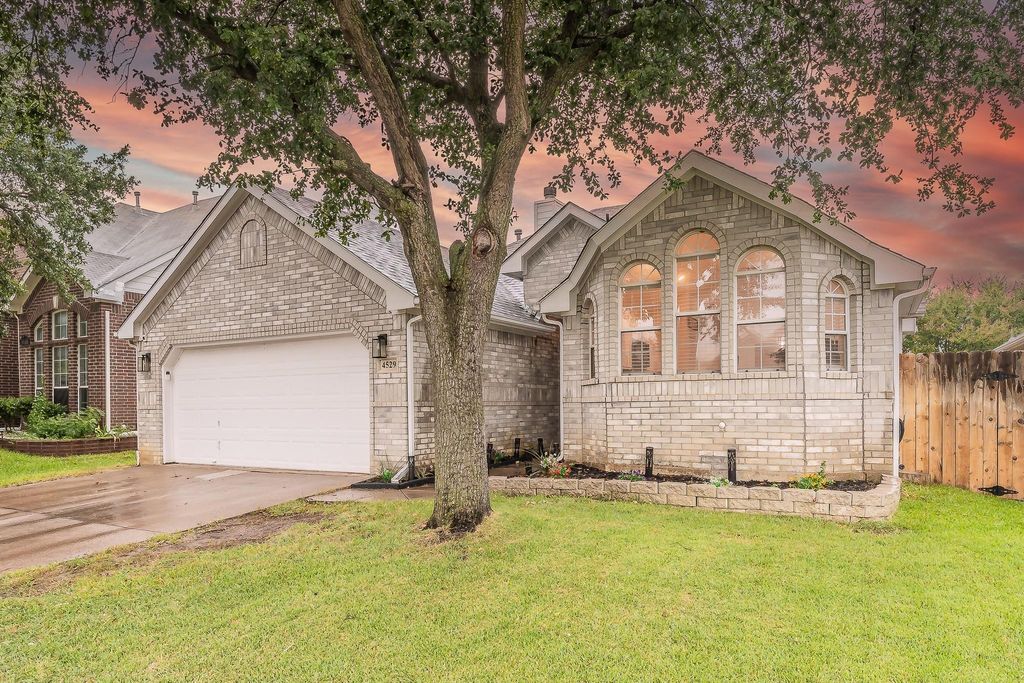 View of front of house with driveway, an attached garage, brick siding, and stone siding