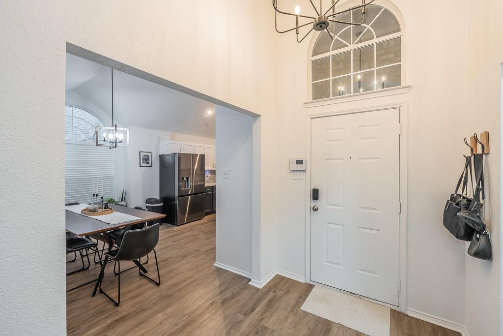 Foyer entrance featuring a chandelier, light wood-type flooring, and a towering ceiling