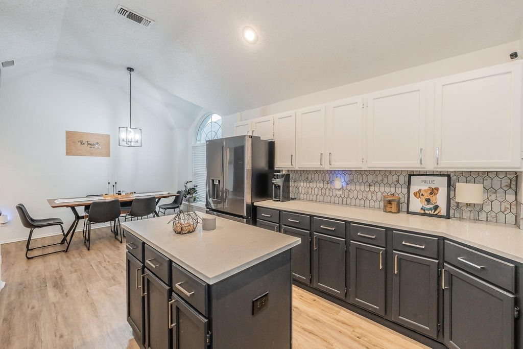 Kitchen with lofted ceiling, a center island, white cabinets, tasteful backsplash, and hanging light fixtures