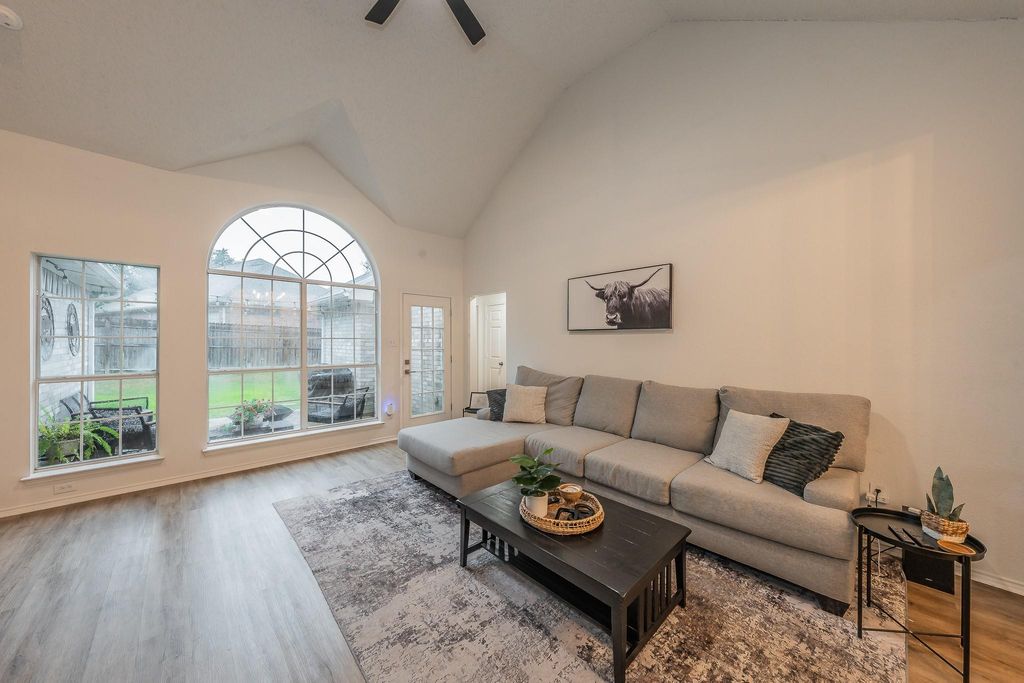 Living room with wood finished floors, high vaulted ceiling, and a ceiling fan