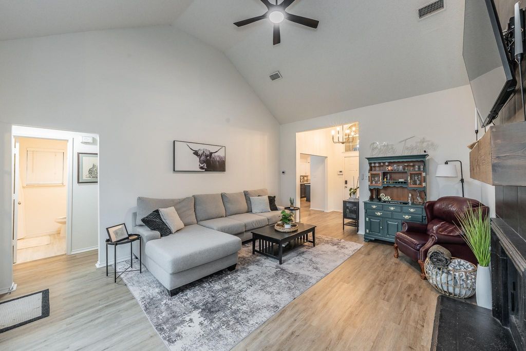 Living room with high vaulted ceiling, light wood-style floors, a ceiling fan, and a chandelier