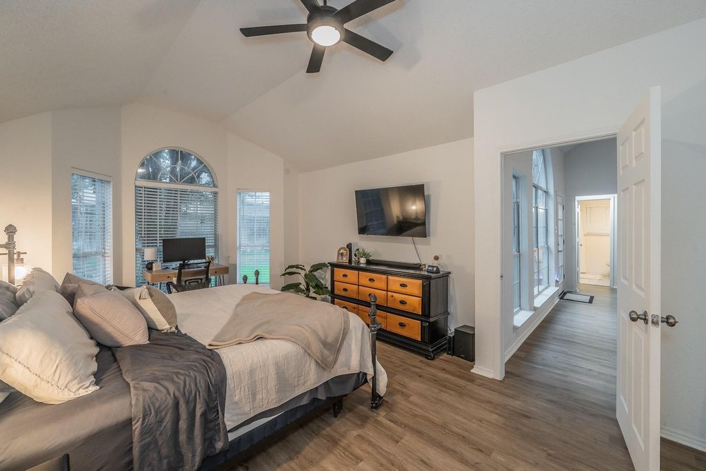 Bedroom featuring multiple windows, wood finished floors, vaulted ceiling, ceiling fan, and access to outside