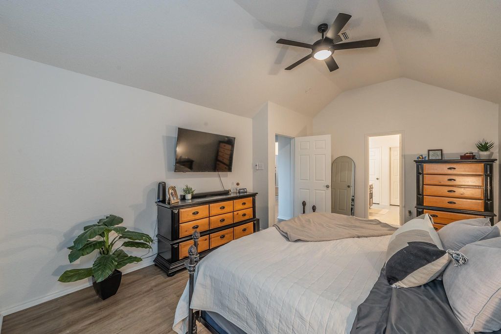 Bedroom featuring light wood finished floors, vaulted ceiling, and a ceiling fan