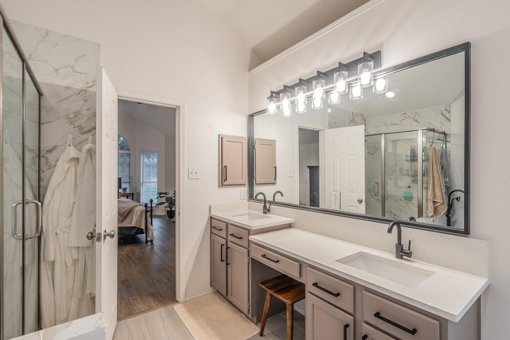 Full bath with a marble finish shower, ensuite bath, double vanity, and light wood-type flooring