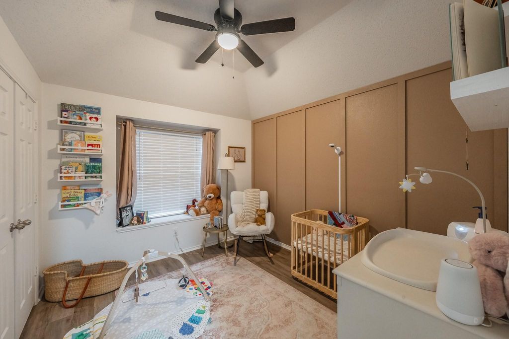 Bedroom featuring a nursery area, light wood-style floors, ceiling fan, and a closet