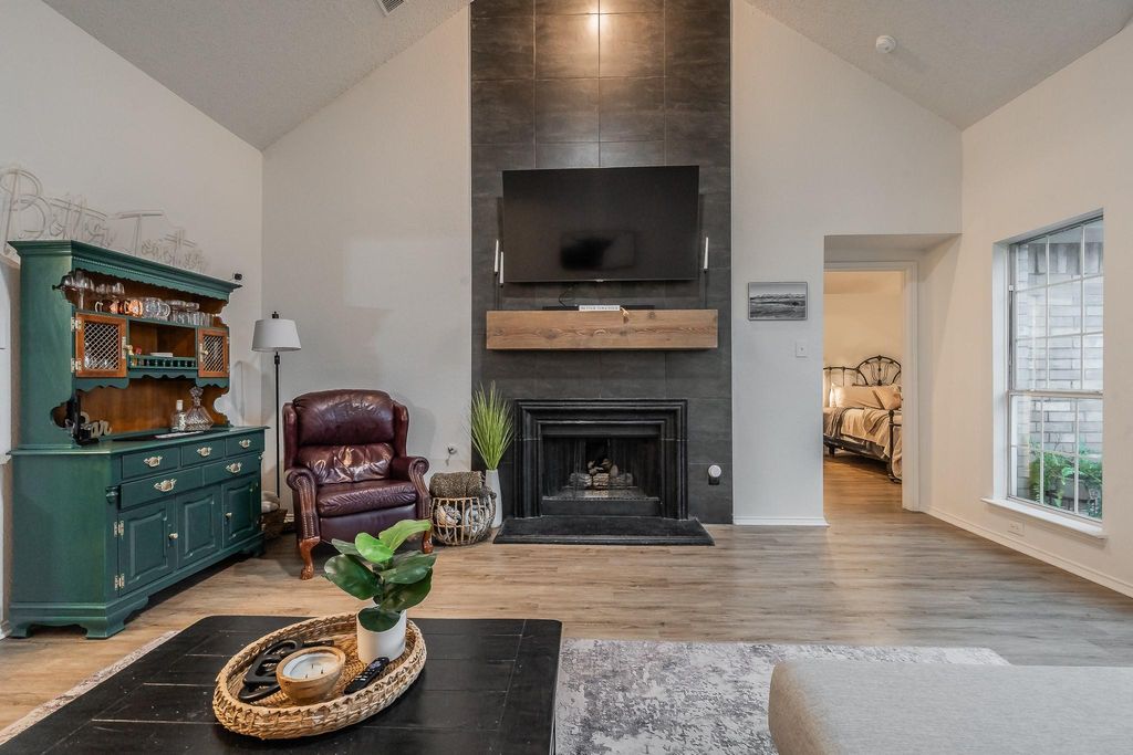 Living room featuring high vaulted ceiling, light wood-style flooring, and a fireplace