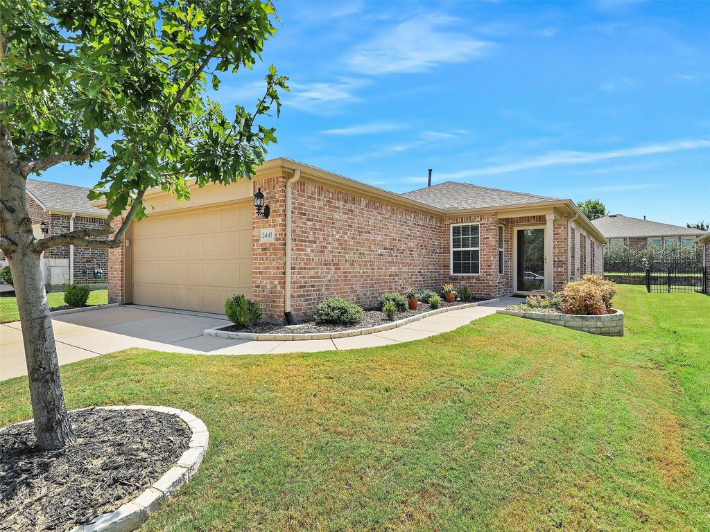 Ranch-style home featuring concrete driveway, a front lawn, an attached garage, and brick siding