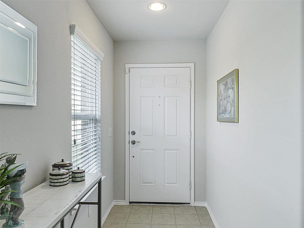 Doorway with tile patterned flooring and baseboards