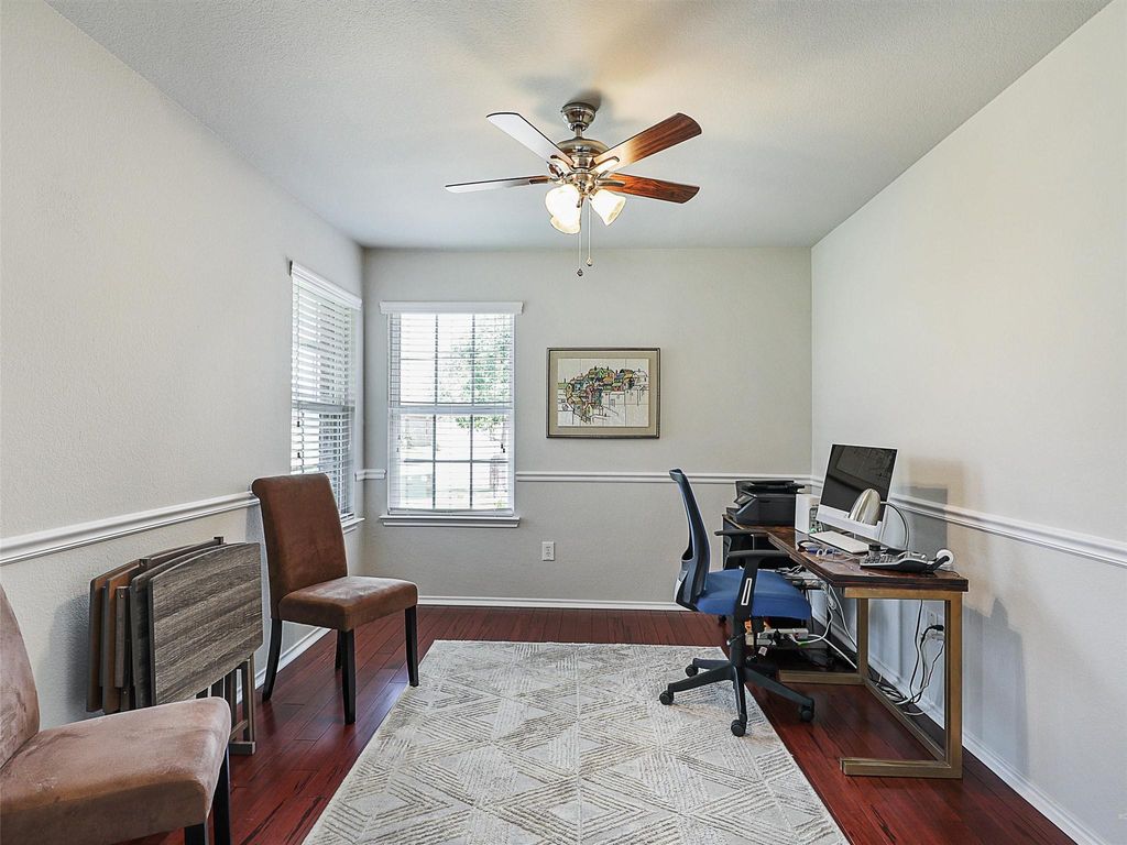 Office space with dark wood-type flooring and a ceiling fan