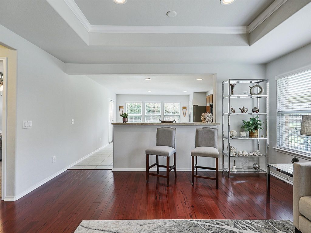 Kitchen featuring a raised ceiling, dark wood-style flooring, a breakfast bar area, ornamental molding, and recessed lighting