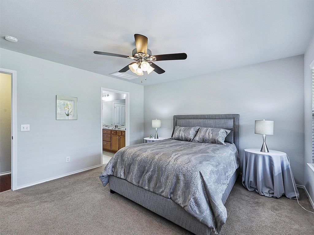 Bedroom with ceiling fan, carpet, and connected bathroom