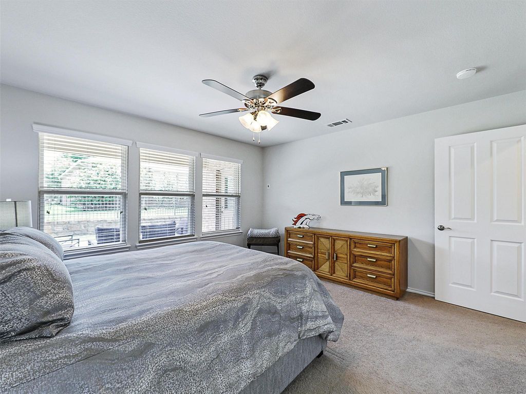 Bedroom with light colored carpet and a ceiling fan