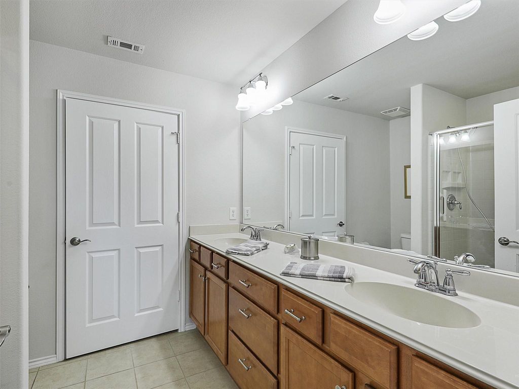 Bathroom with a stall shower, light tile patterned flooring, and double vanity