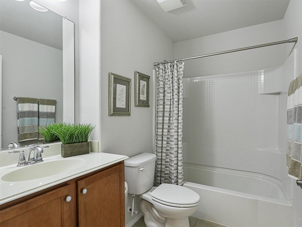 Bathroom featuring shower / bath combo with shower curtain, vanity, and tile patterned flooring