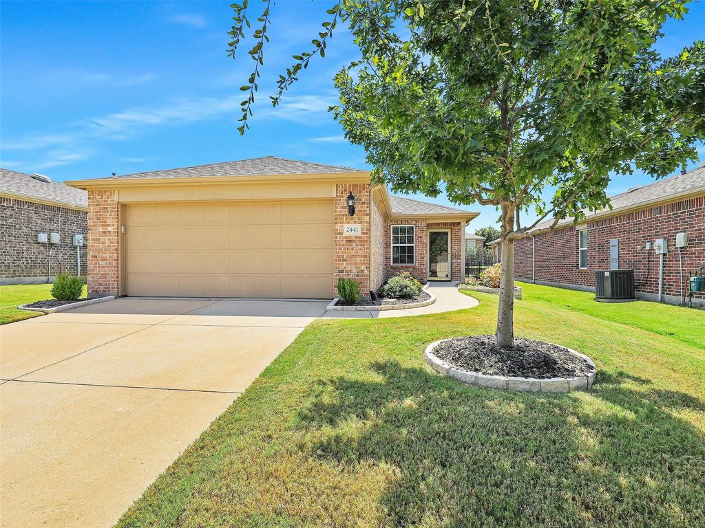 Ranch-style house featuring driveway, brick siding, a front lawn, an attached garage, and a shingled roof