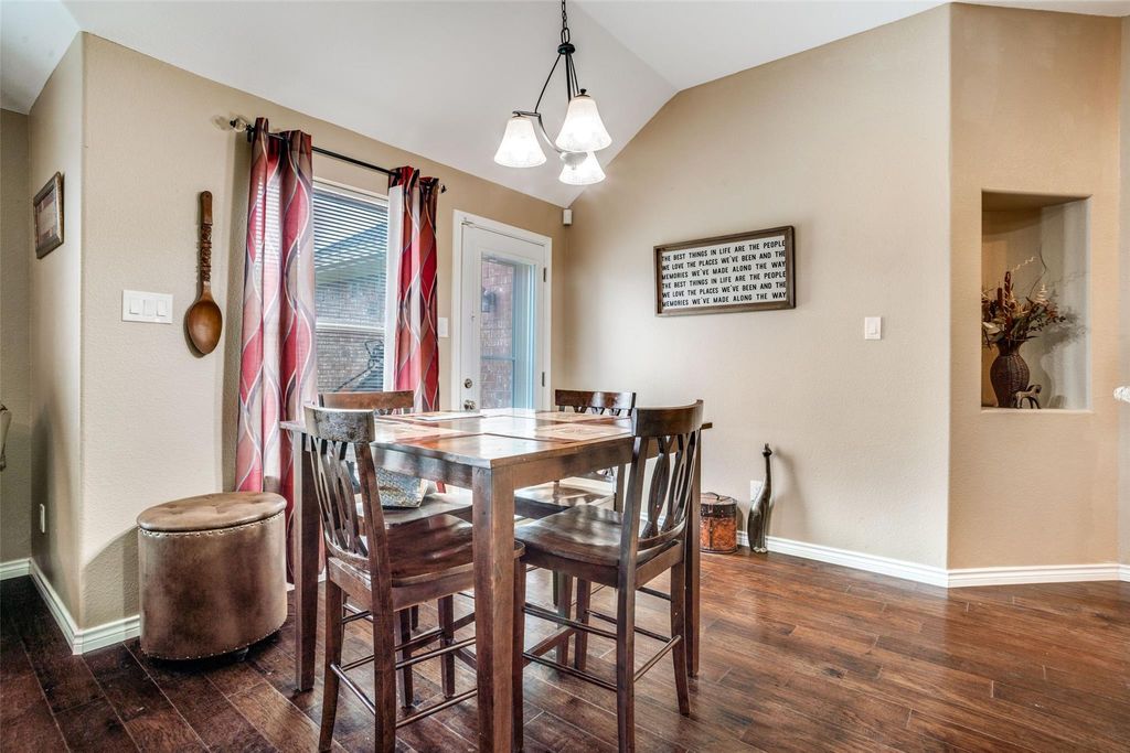 Dining area with dark wood finished floors, vaulted ceiling, and a chandelier