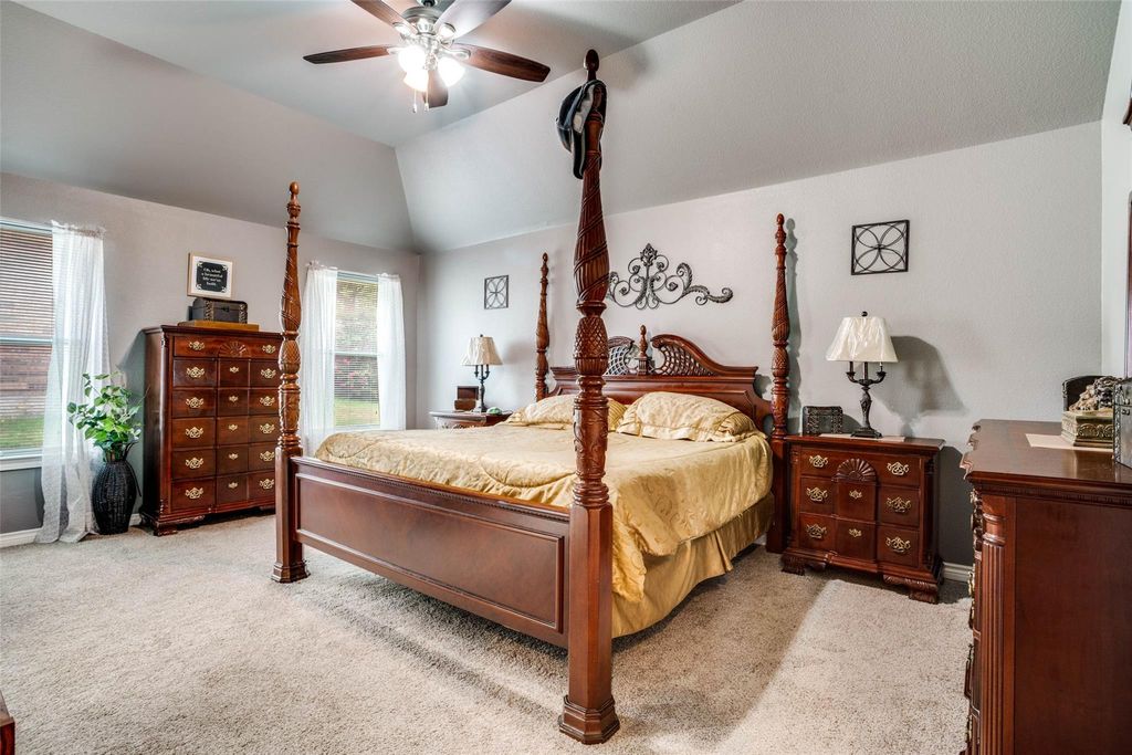 Bedroom featuring light carpet, ceiling fan, and vaulted ceiling