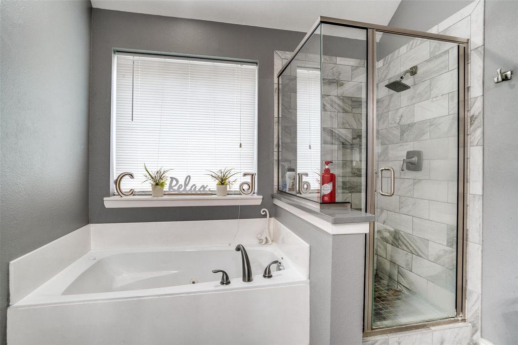 Bathroom with a stall shower, a garden tub, and a textured wall