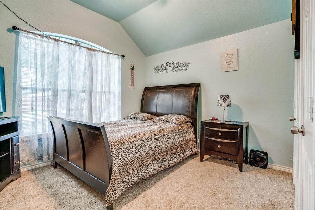 Carpeted bedroom featuring lofted ceiling and baseboards