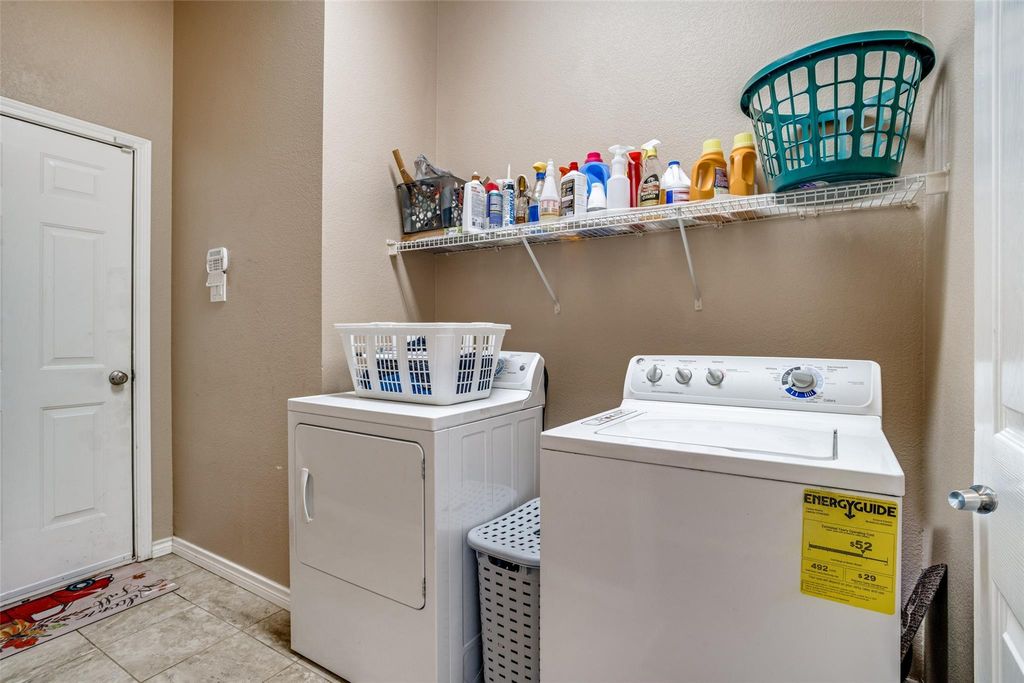 Washroom featuring a textured wall, independent washer and dryer, and light tile patterned floors