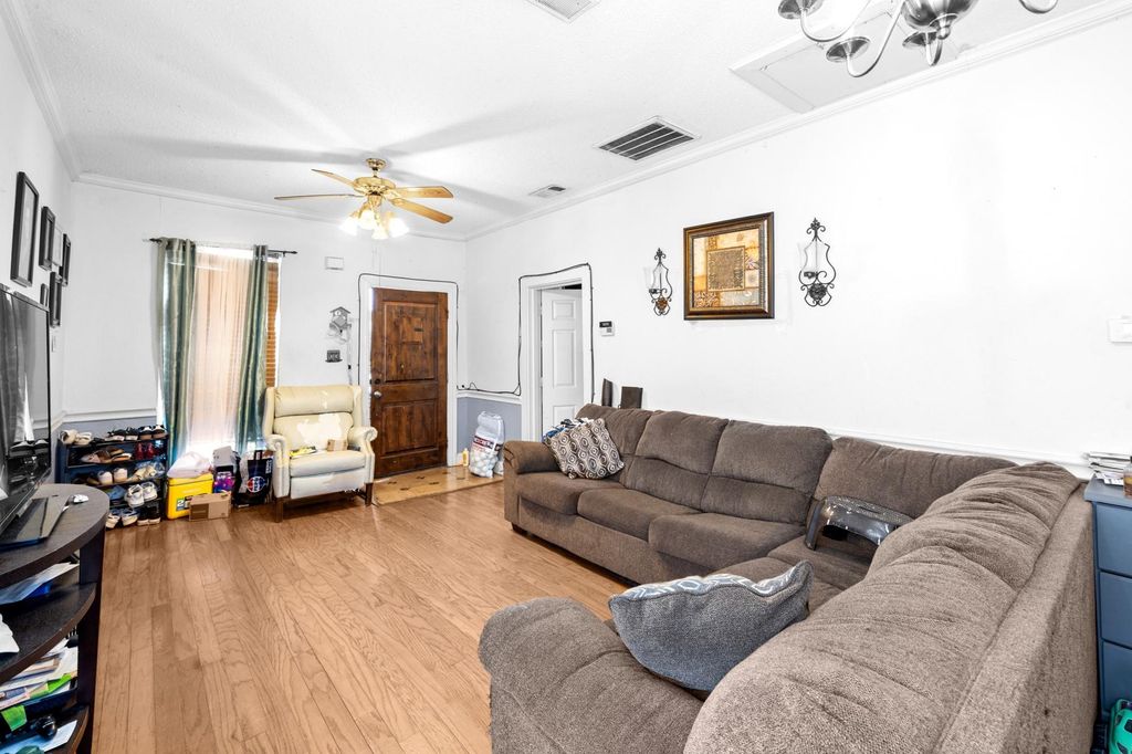 Living room with ornamental molding, wood finished floors, and a ceiling fan