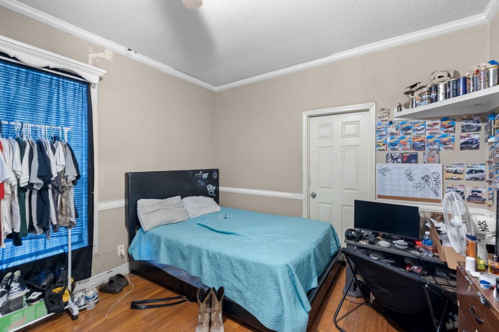 Bedroom featuring wood finished floors, a textured ceiling, crown molding, and an office area
