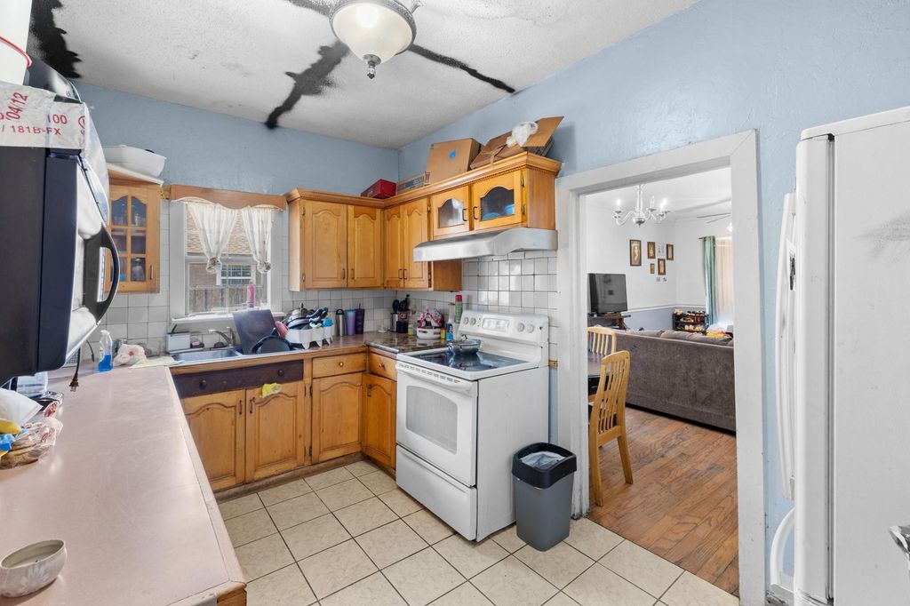 Kitchen featuring white appliances, tasteful backsplash, light tile patterned floors, and brown cabinetry