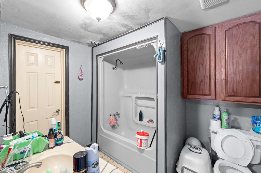 Bathroom featuring washtub / shower combination, vanity, and light tile patterned flooring