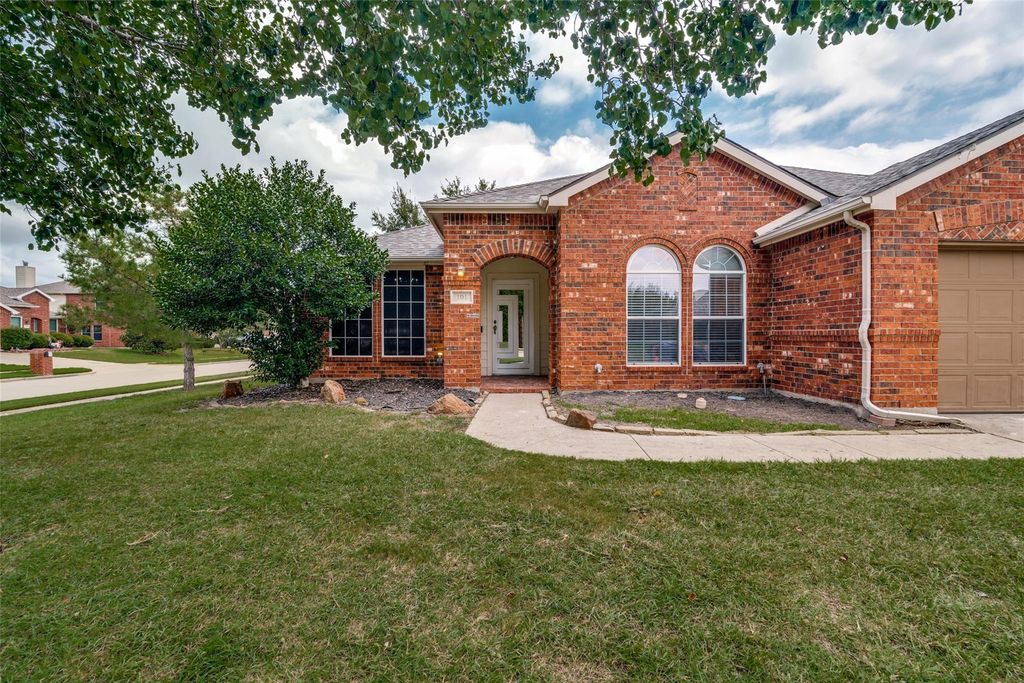 View of front of home featuring a front lawn, brick siding, an attached garage, and a shingled roof