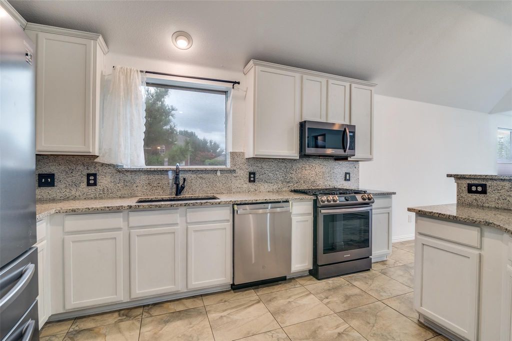 Kitchen featuring backsplash, stainless steel appliances, healthy amount of natural light, and light stone countertops