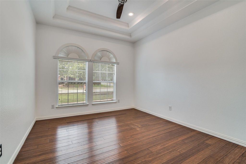 Bedroom with dark wood finished floors, a tray ceiling, crown molding, and recessed lighting