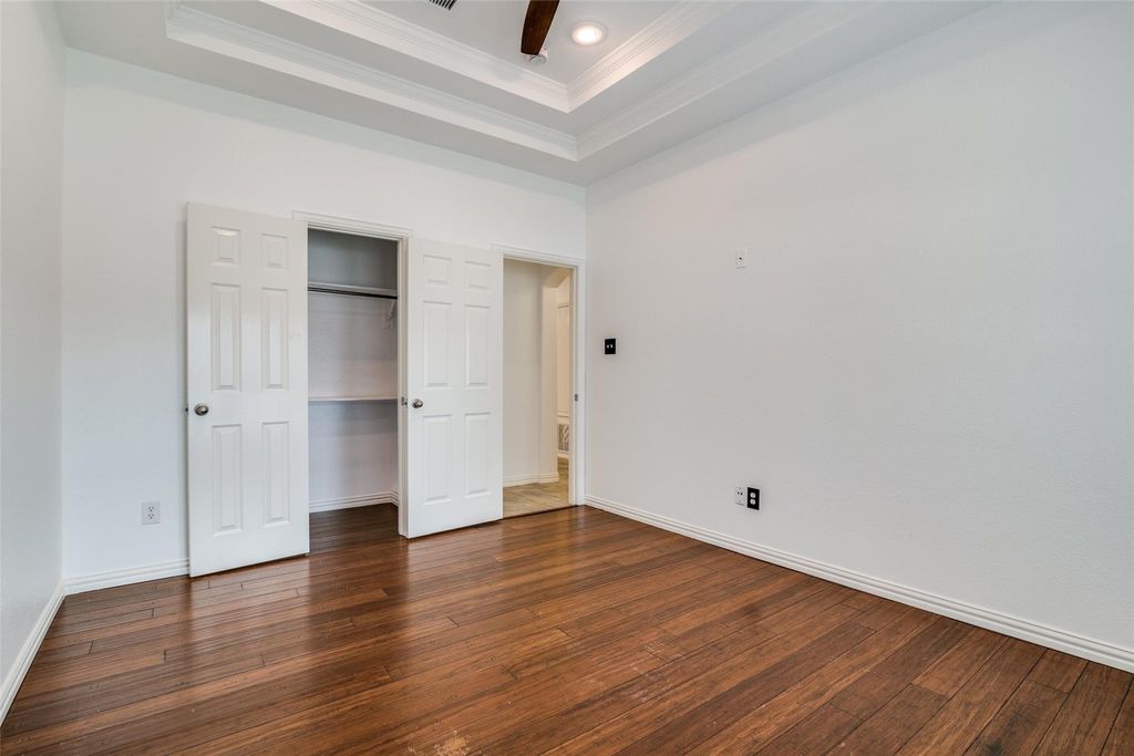 Bedroom with a raised ceiling, ornamental molding, dark wood-style flooring, recessed lighting, and ceiling fan