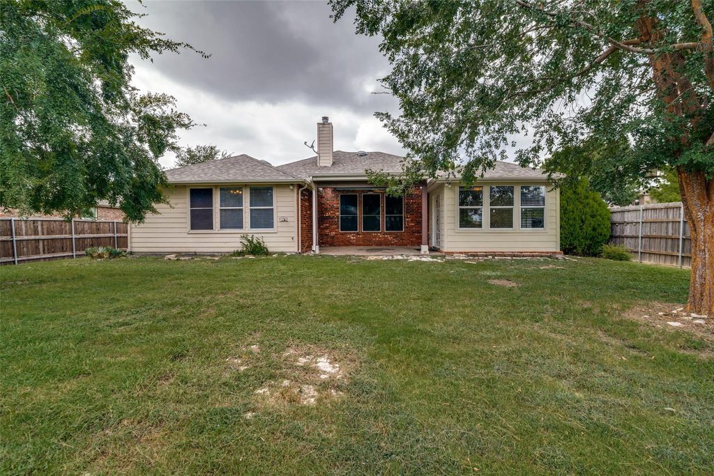 Back of house with a fenced backyard, a patio, a chimney, and roof with shingles