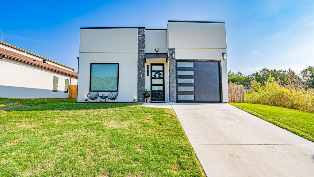 Modern home featuring driveway, stucco siding, a front yard, and a garage