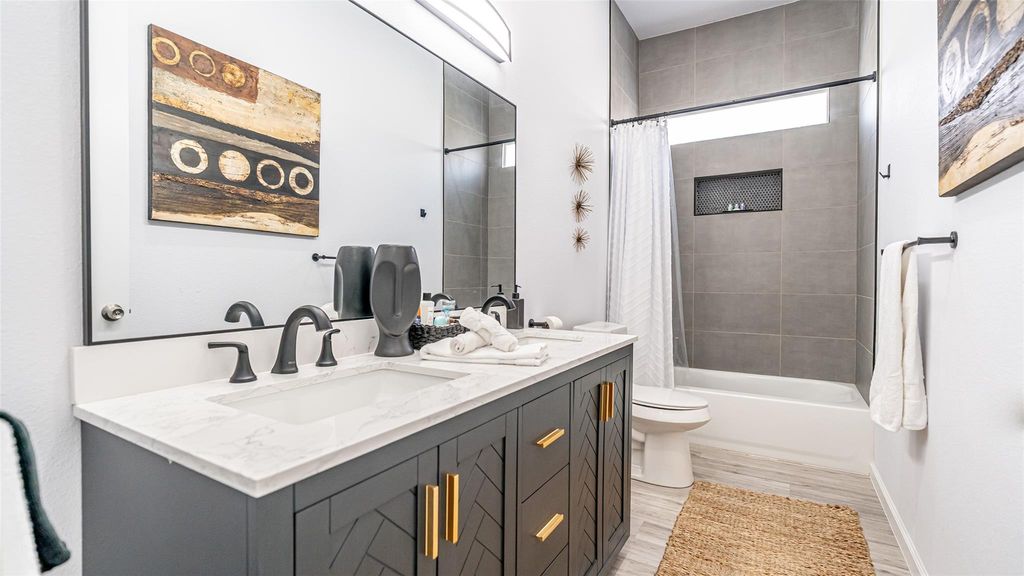 Full bath with shower / tub combo, double vanity, and light wood finished floors