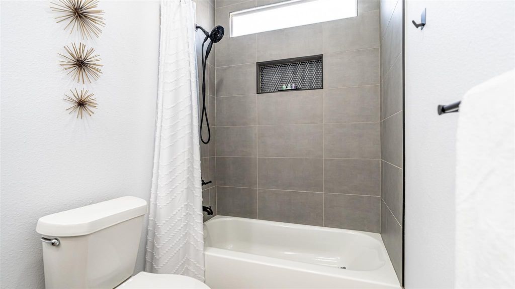 Full bathroom with shower / bath combo and a textured wall