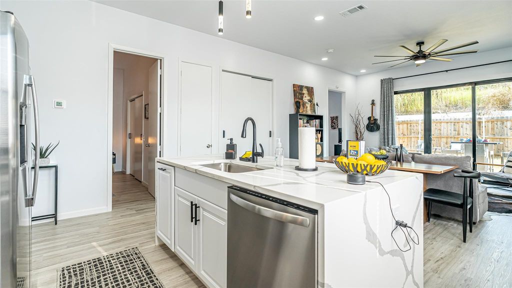 Kitchen featuring stainless steel appliances, light stone countertops, white cabinetry, recessed lighting, and open floor plan