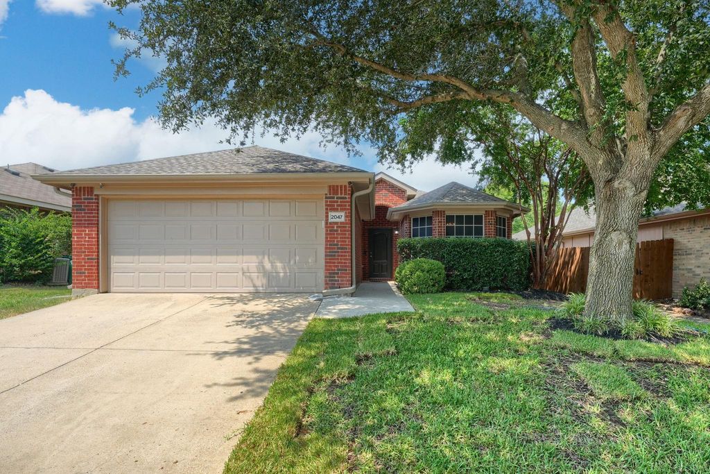 Ranch-style house featuring brick siding, driveway, roof with shingles, and a garage