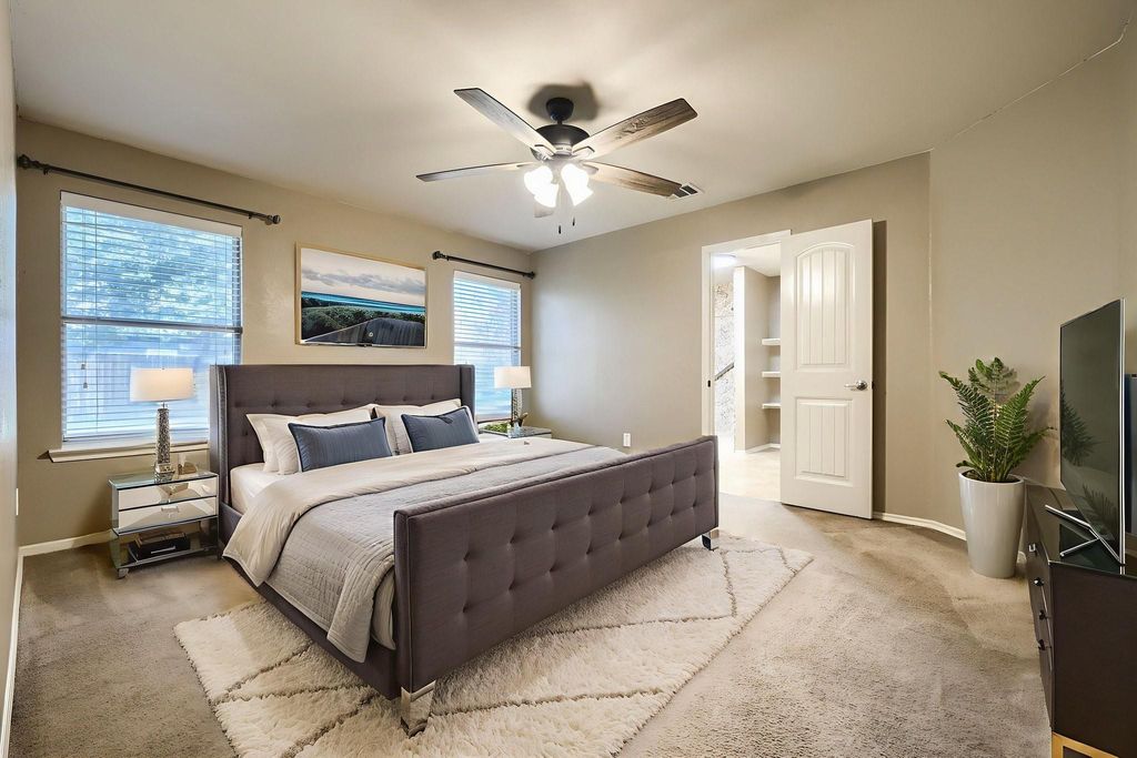 Bedroom with carpet floors, multiple windows, a ceiling fan, and connected bathroom