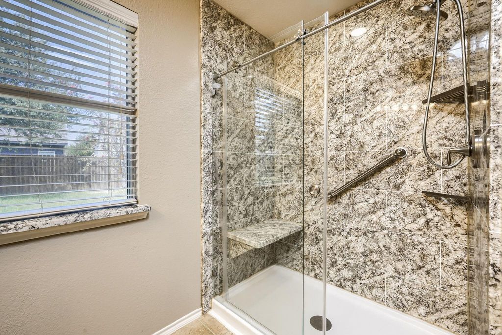 Full bathroom with a textured wall, a shower stall, and plenty of natural light