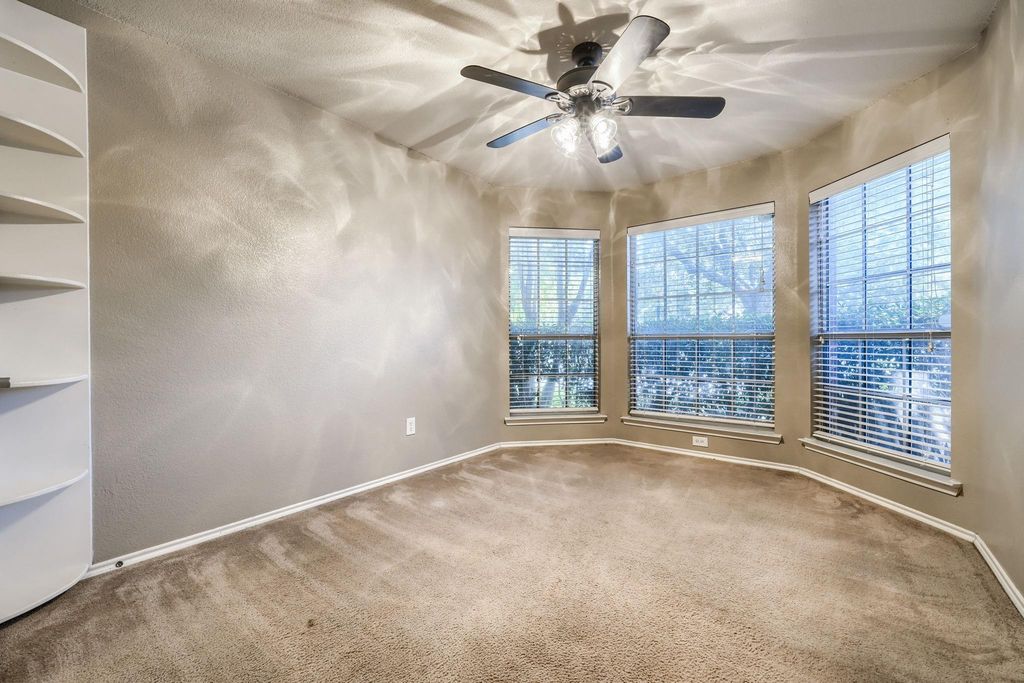 Carpeted bedroom featuring a ceiling fan and a textured wall
