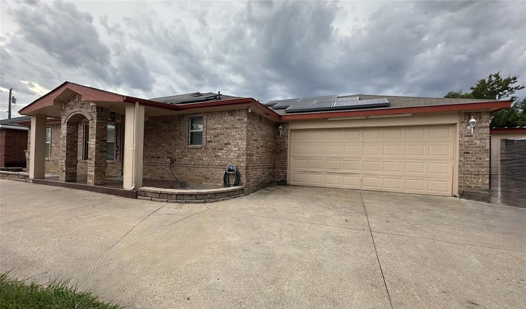 Single story home featuring brick siding, roof mounted solar panels, and concrete driveway